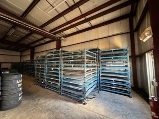 Multiple stacks of disassembled blue stack racks arranged in warehouse
