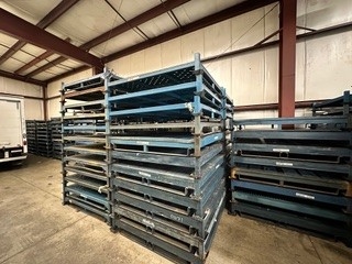 Tall stacks of disassembled blue stack rack frames ready for transport