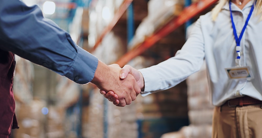 Two people shaking hands in agreement inside a warehouse