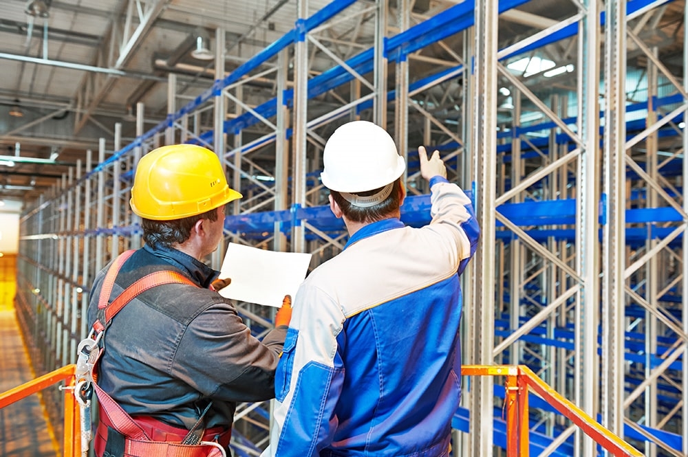 Rack installers assessing a plan while working on a pallet rack installation