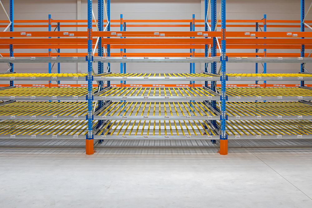 Multi-level carton flow rack system with yellow roller tracks and blue uprights, designed for FIFO inventory management in warehouse storage applications