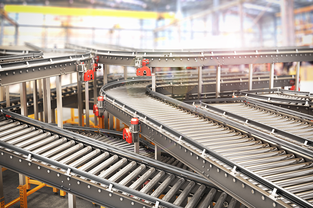 Motorized roller conveyor system with multiple curves and levels inside a large industrial warehouse.