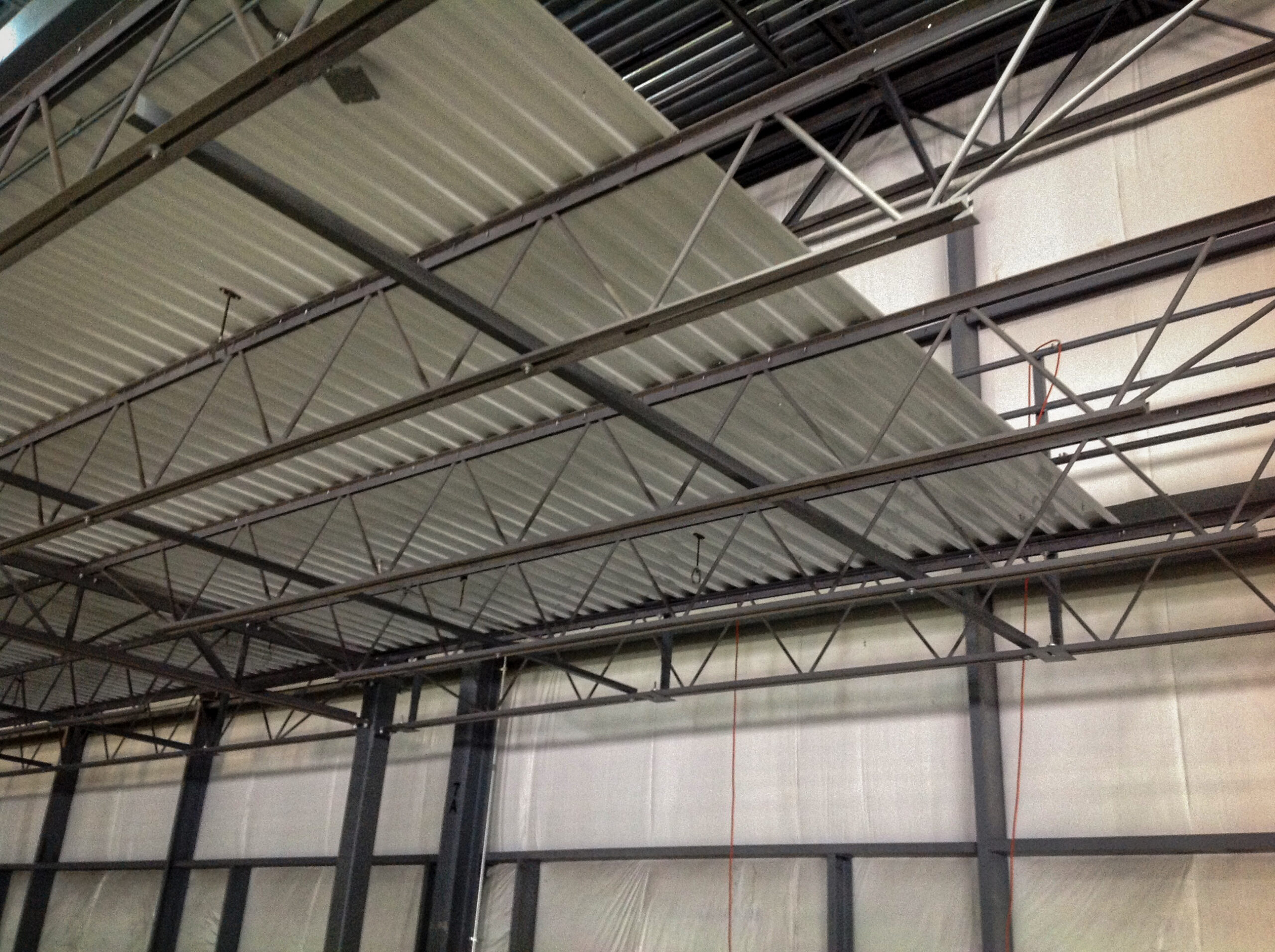 A photo of Mezzanine B-Decking taken from underneath the mezzanine. Girders, Joists, and Columns are also visible.