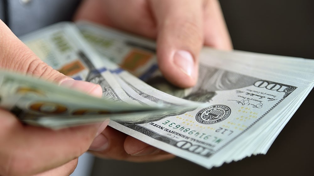 Man holding pile of 100 dollar bills